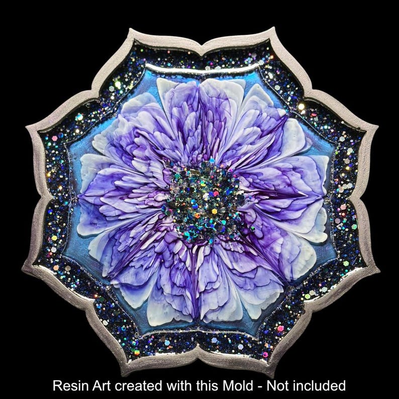 Op de afbeelding: Een harskunstwerk met een grote, gestileerde paarse bloem met witte accenten, tegen een lichtblauwe achtergrond. Het heeft een zilverkleurige, geschulpte rand met donkerblauwe glitter. De tekst onderaan luidt: Resin Art created with this Mold - Not included.