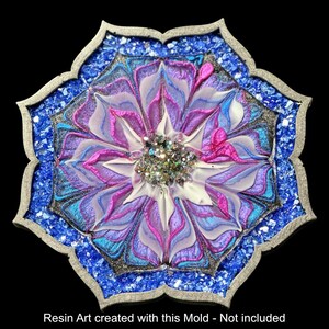 Op de afbeelding: Een harskunstwerk met een bloemenontwerp. Het midden heeft glitter, omringd door bloemblaadjes in wit, roze, paars en blauw. Het is omlijst met een zilveren rand en blauw gemalen glas.