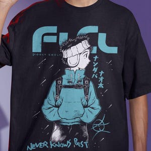 Puede incluir: Camiseta negra con la palabra "FLCL" en turquesa y una ilustración de estilo anime de un personaje con una sudadera con capucha azul. También se ve el texto "NEVER KNOWS BEST".