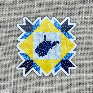 May include: A yellow, blue, and white quilt block featuring a silhouette of the state of West Virginia. The block is made up of various geometric shapes and patterns.