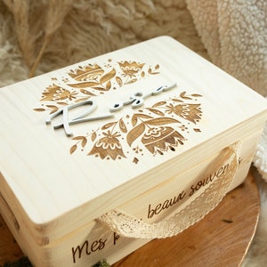 Peut inclure: Une boîte en bois avec un motif floral et le nom "Rosa" gravé sur le couvercle. La boîte a une poignée en dentelle et le texte "mes beaux souvenirs" est gravé sur le côté.