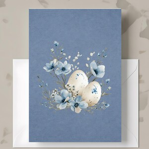 May include: A blue greeting card with a watercolor design featuring two speckled eggs and blue flowers. The card is accompanied by a white envelope, perfect for Easter or spring celebrations.