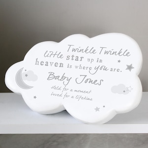 May include: A white cloud-shaped plaque with the text "Twinkle Twinkle little star up in heaven is where you are. Baby Jones. Held for a moment loved for a lifetime." Includes a moon and stars design.