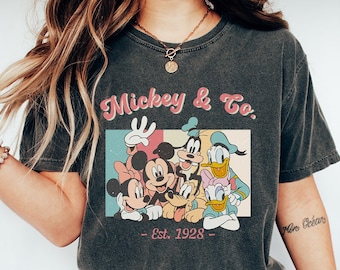 May include: A black t-shirt with a vintage-style graphic of Mickey Mouse and friends. The graphic includes the text "Mickey & Co. - Est. 1928 - ".