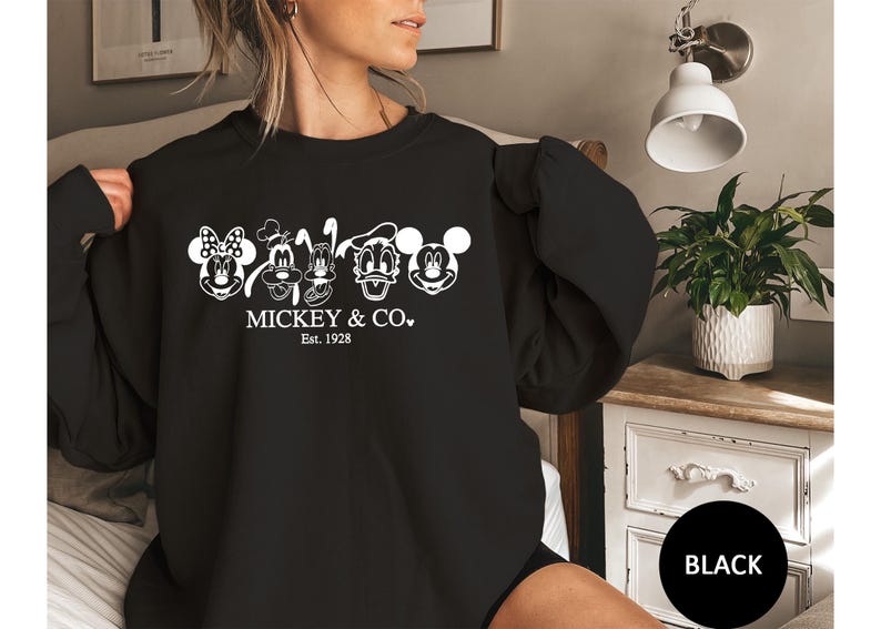 May include: Black sweatshirt with white outlines of Mickey Mouse, Minnie Mouse, Donald Duck, Goofy, and Pluto. The text "Mickey & Co. Est. 1928" is printed below the characters. A classic style sweatshirt.