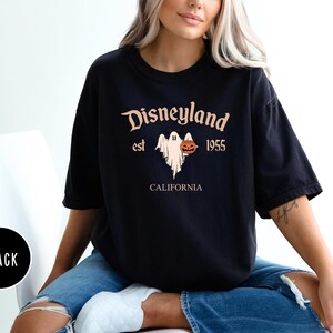 Op de afbeelding: Zwart T-shirt met een grafische print van een geest die een pompoen vasthoudt. De tekst "Disneyland est 1955 Californi&euml;" staat op het T-shirt gedrukt.