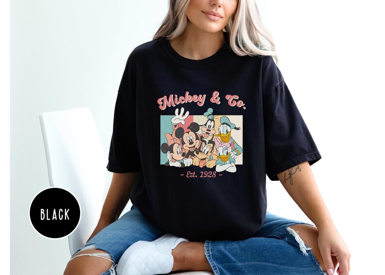 May include: Black t-shirt with a vintage-style graphic of Mickey Mouse, Minnie Mouse, Donald Duck, Goofy, and Pluto. The graphic includes the text "Mickey & Co. - Est. 1928 - "