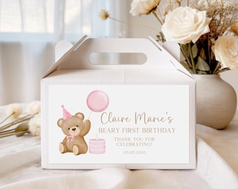 May include: White gable box with a handle, featuring a watercolor illustration of a teddy bear wearing a party hat and holding a pink balloon. Text reads "Claire Marie's Beary First Birthday" and "Thank you for celebrating!" with a date.