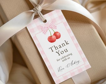 Peut inclure: Une étiquette cadeau avec une bordure rose à carreaux et une illustration à l'aquarelle de deux cerises. L'étiquette indique "Thank You" et comprend le texte "for celebrating with us" et "Love Aubrey". L'étiquette est attachée à un cadeau emballé avec un ruban crème.