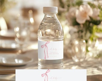 May include: Pink and white baby shower water bottle labels with a pink ribbon and the text "Oh baby" and "Tatiana's Baby Shower 12.12.2023".
