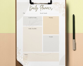 May include: A white daily planner with a brown clipboard. The planner has sections for the day, goal for today, priority, daily checklist, events, and notes. The planner is decorated with a floral design.
