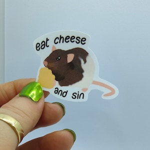 Op de afbeelding: Een sticker met een bruin-witte rat die kaas eet. De tekst "eat cheese and sin" staat in een tekstballon. De rat houdt een stuk gele kaas vast.