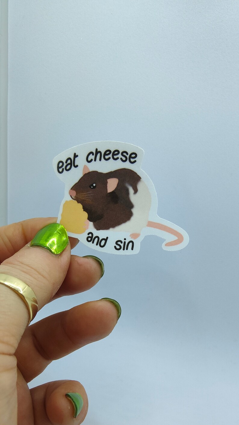 Op de afbeelding: Een sticker met een bruin-witte rat die kaas eet. De tekst "eat cheese and sin" staat in een tekstballon. De rat houdt een stuk gele kaas vast.