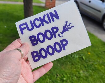 Op de afbeelding: Een witte sticker met de tekst "FUCKIN BOOP BOOOP" in paarse letters. Naast de tekst staat een paars cartoonhoorn met golvende lijnen.