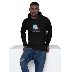 Può includere: Una felpa con cappuccio nera con un logo rosa e blu che dice "Im Gilty Art" e "Unwrap Joy, Share Smiles!"