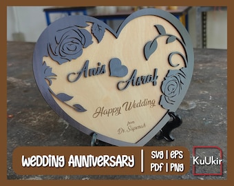 May include: A wooden heart-shaped plaque with a decorative floral design and the names "Anis" and "Abrar" engraved on it. The plaque also includes the text "Happy Wedding" and "from Dr. Sapenah".