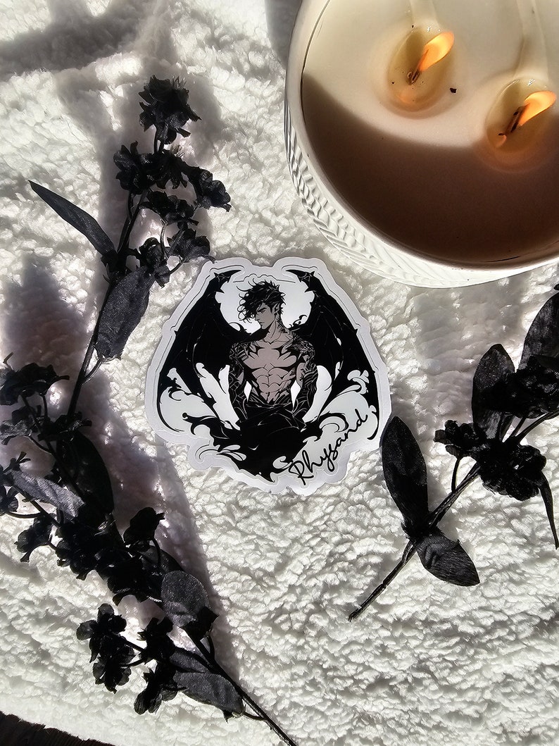 Puede incluir: Pegatina en blanco y negro con una figura musculosa alada sobre un fondo oscuro. La pegatina tiene la palabra "Rhyyand" escrita en cursiva en la parte inferior.