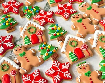 May include: Assortment of Christmas-themed sugar cookies decorated with red, green, and white icing. The cookies are shaped like gingerbread people, houses, stars, and Christmas trees.