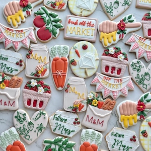 Könnte beinhalten: Eine Auswahl an dekorierten Zuckerkeksen mit Bauernhof-Thema. Die Kekse zeigen Karotten, Tomaten, Erdbeeren und Banner mit der Aufschrift "Off the Market" und "Future Mrs.". Einige Kekse haben die Buchstaben "M&M".