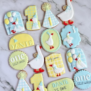 Custom first birthday sugar cookies with hand-decorated geese, party hats, balloons, “Parkery Ryan is One,” "custom name" “Silly Goose,” and number 1 designs in soft sage green, beige, white, and peach tones — perfect for a goose-themed birthday party or personalized baby celebration.