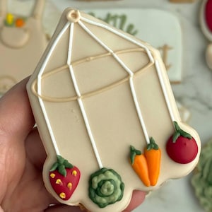 Farmers market-themed baby shower sugar cookies featuring hand-decorated designs like “little sprout,” baby onesies with vegetables, carrots, corn, strawberries, tomatoes, baby bottles, mason jars, leafy greens, and baby mobiles. Adorned with soft green, beige, orange, and red royal icing, these custom cookies are perfect for a “locally grown” or garden baby shower theme, gender-neutral celebrations, and personalized baby gifts.