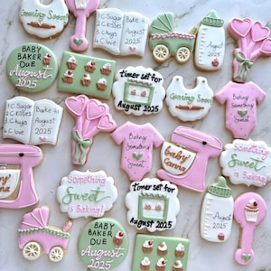 May include: A collection of baby shower-themed sugar cookies in various shapes, including a bib, baby bottle, onesie, and a baby carriage. The cookies are decorated with pink, green, and white icing, with text that reads "Baby Baker Due August 2025" and "Something Sweet is Baking!"