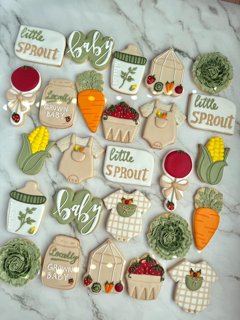 Farmers market-themed baby shower sugar cookies featuring hand-decorated designs like “little sprout,” baby onesies with vegetables, carrots, corn, strawberries, tomatoes, baby bottles, mason jars, leafy greens, and baby mobiles. Adorned with soft green, beige, orange, and red royal icing, these custom cookies are perfect for a “locally grown” or garden baby shower theme, gender-neutral celebrations, and personalized baby gifts.