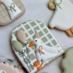 Custom first birthday sugar cookies with hand-decorated geese, party hats, balloons, “Parkery Ryan is One,” "custom name" “Silly Goose,” and number 1 designs in soft sage green, beige, white, and peach tones — perfect for a goose-themed birthday party or personalized baby celebration.