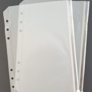 May include: Two clear plastic zippered pouches with holes for a binder. The pouches are stacked on top of each other.