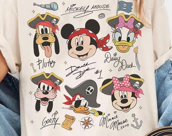Może przedstawiać: Kremowa koszulka z motywem pirackim z Myszką Miki i przyjaciółmi. Grafika zawiera Plutona, Myszka Miki, Daisy, Donalda, Goofy'ego i Minnie Mouse, każdy w pirackim stroju. Koszulka zawiera również tekst "Mickey Mouse" i "Minnie Mouse xoxo".
