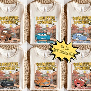 May include: Cream-colored t-shirts featuring the "Radiator Springs" design with various cartoon car characters. Each shirt has a different car graphic and the text "CUSTOM NAME". A yellow starburst graphic says "WE DO ANY CHARACTERS".