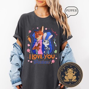 May include: Dark gray t-shirt featuring cartoon characters Nick Wilde and Judy Hopps from Zootopia, with the text "I Love You Partner!" and decorative elements. The shirt is a comfortable, casual style.