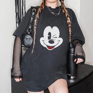 May include: Black oversized t-shirt with a white Mickey Mouse graphic. The shirt has a mesh overlay on the sleeves.