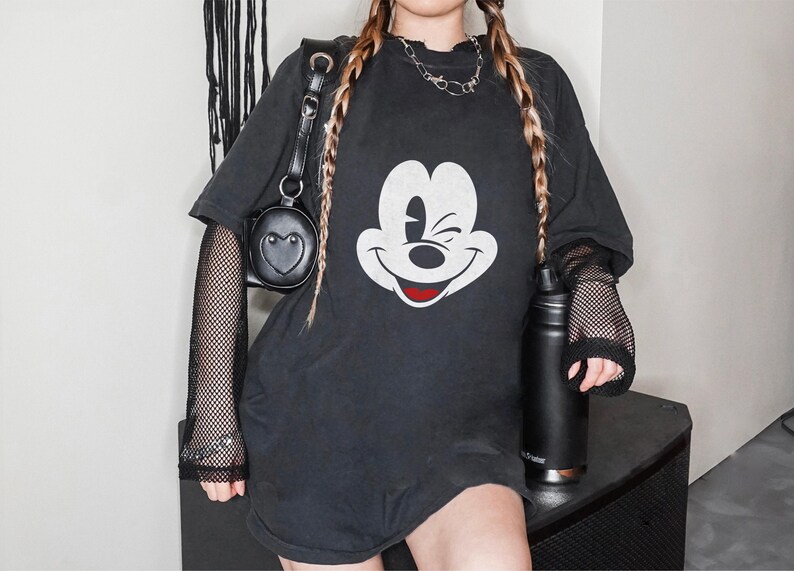 May include: Black oversized t-shirt with a white Mickey Mouse graphic. The shirt has a mesh overlay on the sleeves.