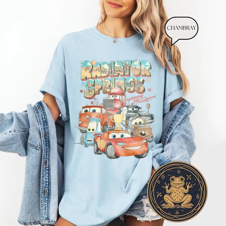 May include: Light blue t-shirt with a graphic of the Cars characters from the movie Cars. The graphic includes the text "Radiator Springs" and "Lightning McQueen".