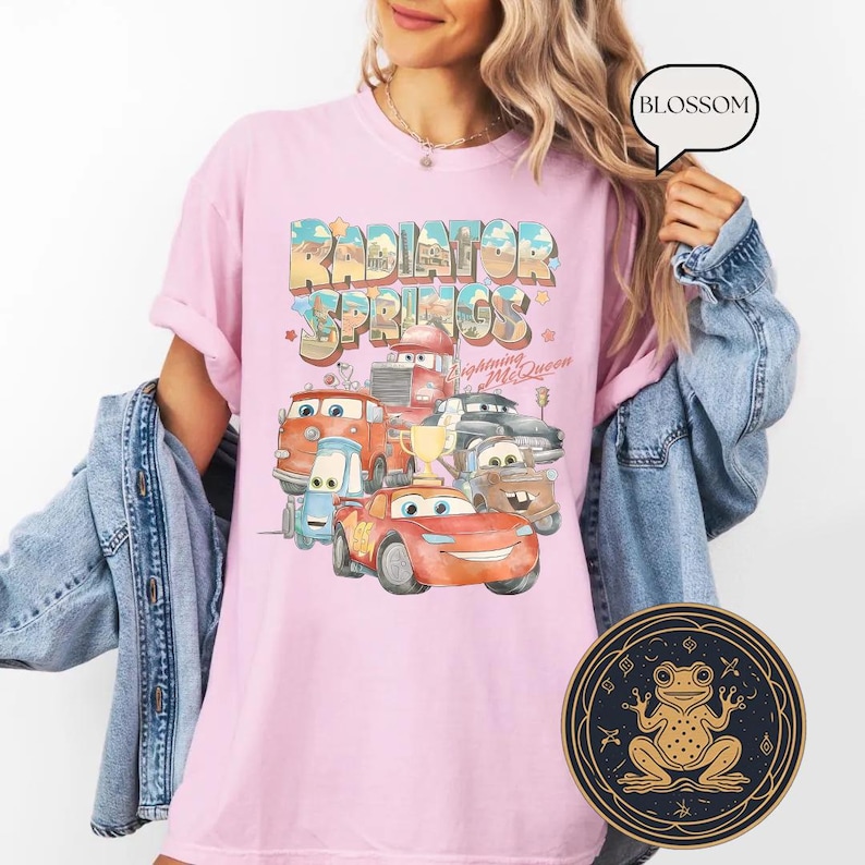 May include: Pink t-shirt with a graphic of the Cars characters from the movie Cars. The graphic says "Radiator Springs" and features Lightning McQueen.