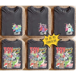 May include: Six charcoal gray t-shirts featuring Toy Story characters. Designs include the aliens, Zurg, and Buzz Lightyear, with personalized names. The bottom shirts display a larger Toy Story graphic with multiple characters.