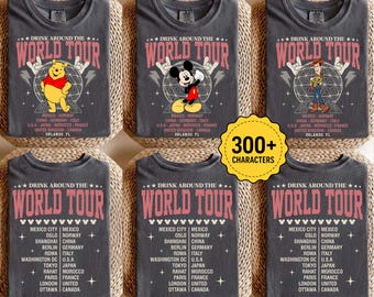May include: A charcoal gray t-shirt featuring the text Drink Around The World Tour in pink. The design includes a graphic of a character, a globe, and a list of cities and countries including Mexico City, Oslo, Shanghai, Berlin, Rome, and Tokyo.
