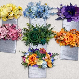 Op de afbeelding: Een assortiment kleurrijke bloemstukken in zilveren rechthoekige containers. De bloemen omvatten gele, blauwe, paarse, roze, groene en oranje bloemen, waardoor een levendige weergave ontstaat. De containers zijn op een lichtgekleurde muur gemonteerd.