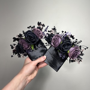 May include: Two black satin gift boxes with purple and black roses and greenery.