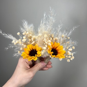 Op de afbeelding: Een klein boeket gedroogde bloemen met twee gele zonnebloemen en wit pampasgras.