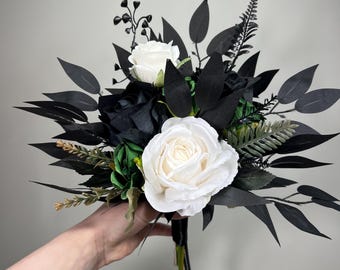 May include: A bridal bouquet with white and black roses, black leaves, and green foliage.