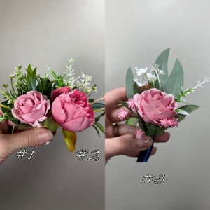 May include: Three pink flower boutonnieres with greenery and white flowers. The boutonnieres are labeled #1, #2, and #3.