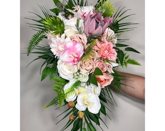 Könnte beinhalten: Ein kaskadierender Brautstrauß mit rosa, weißen und cremefarbenen Blumen, darunter Rosen, Orchideen und eine Protea. Der Strauß ist mit üppigem grünem Laub verziert.