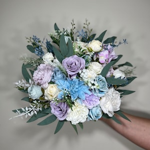 May include: A bouquet of artificial flowers in shades of blue, purple, and white. The bouquet includes roses, hydrangeas, and other flowers.