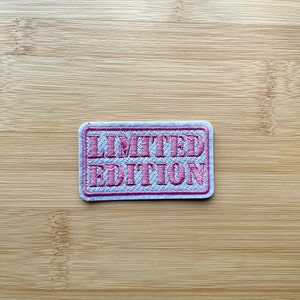 May include: A white patch with a pink embroidered border and the text "LIMITED EDITION" in pink.