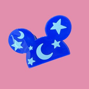 May include: Blue plastic Mickey Mouse ears with a white crescent moon and stars design.