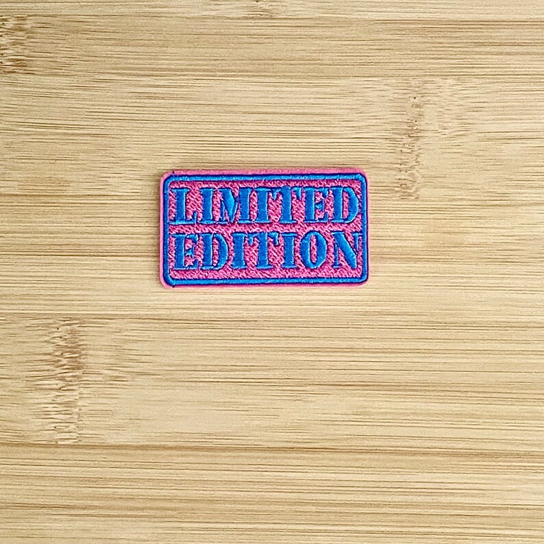 May include: A pink and blue embroidered patch with the text "LIMITED EDITION" in blue.
