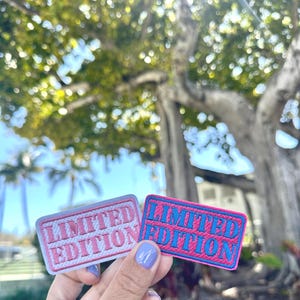 May include: Two embroidered patches with the text "LIMITED EDITION" in pink and blue lettering on a white and pink background.