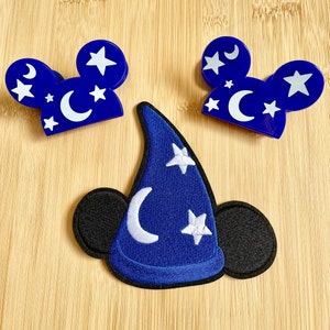 May include: Blue felt Mickey Mouse ears with white stars and moons, and a blue felt sorcerer hat with white stars and moons.